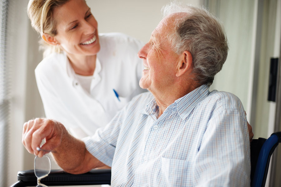 Nurse smiling at elderly on wheelchair